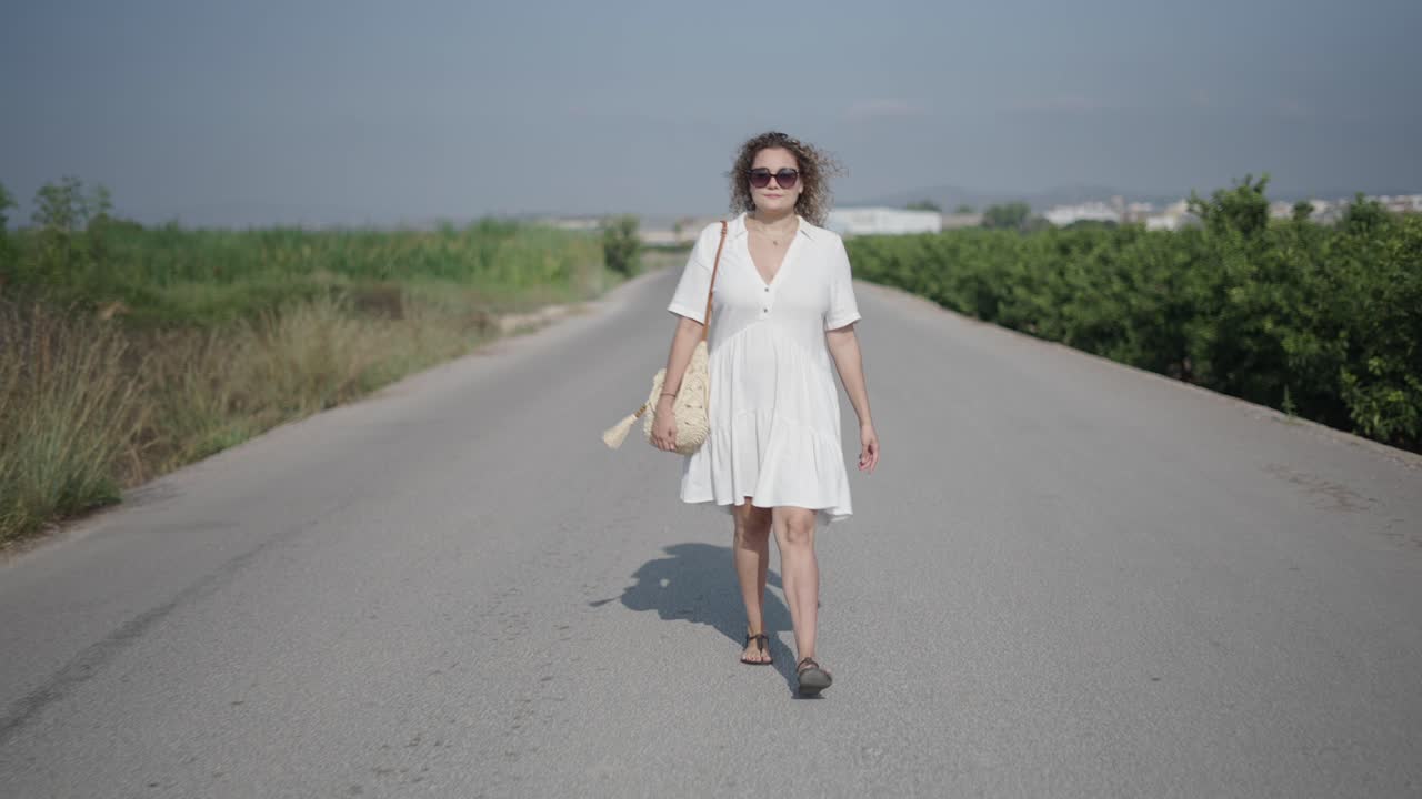 Donna che cammina su una strada di campagna in abito bianco