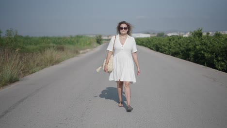 woman walking on a country road in a white dress