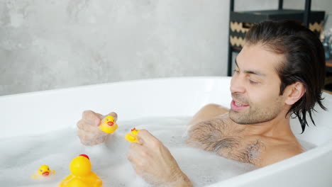 man playing with rubber ducks in a bubble bath