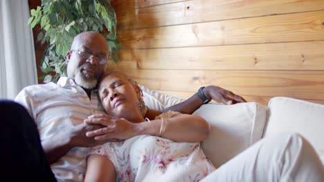 Senior-african-american-couple-lying-on-sofa-at-home,-slow-motion