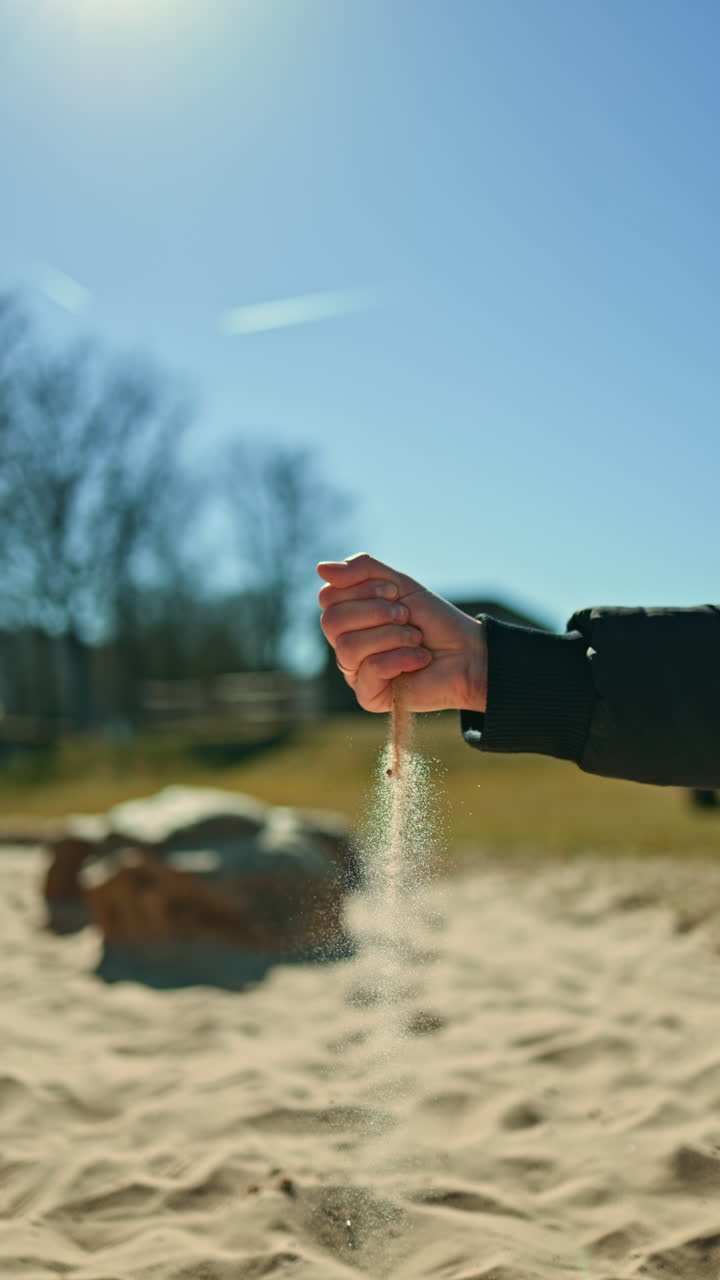 Palms from which yellow sand is pouring. Warm beach sand in women's hands