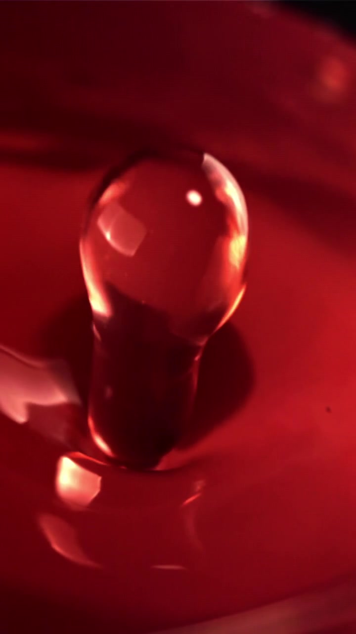 Slow Motion Macro Shot of a Red Liquid Drop Splashing