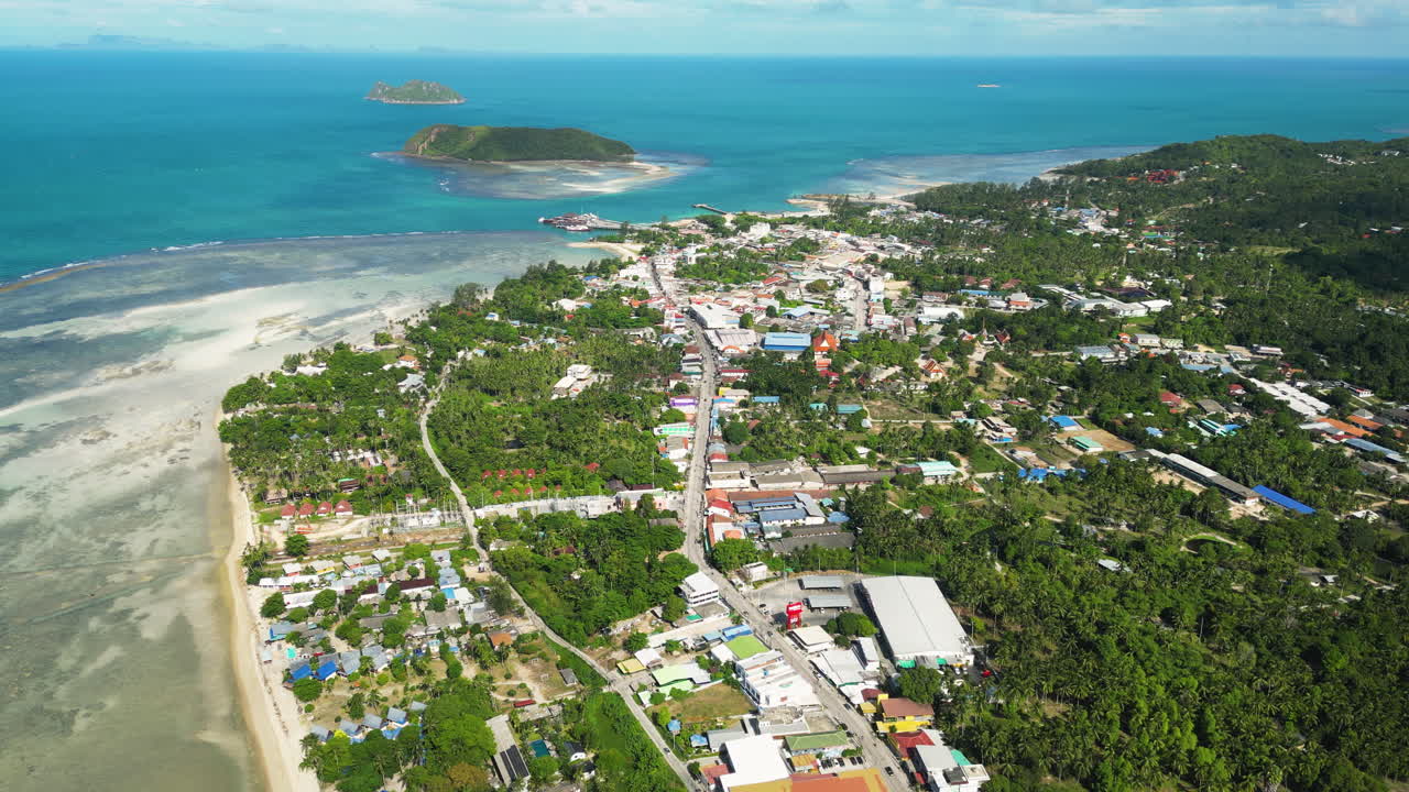 Koh Phangan Island and Thongsala pier with cloud shadows passing over, aerial trucking pan