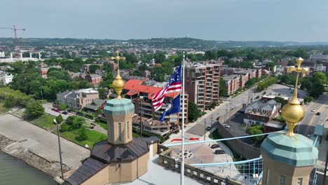 America-and-Kentucky-flags-waving-on-bridge-connecting-Covington,-KY-and-Cincinnati,-Ohio