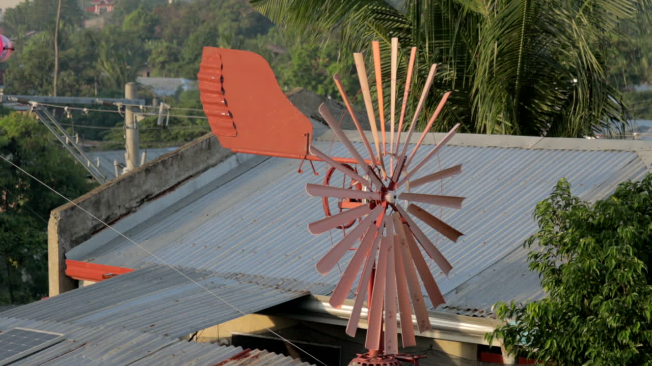 Rust colored spinning windmill with tin roofs in the background. locked off