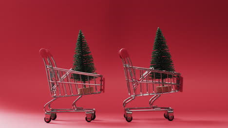 Video-of-shopping-trolley-with-christmas-trees-and-copy-space-on-red-background