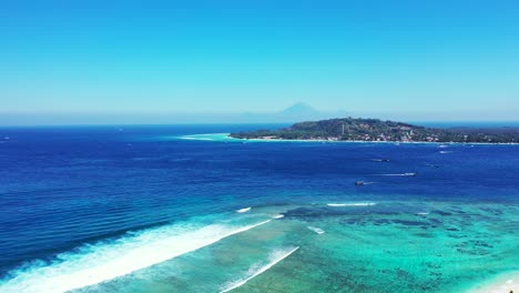 beautiful seaside with boats sailing on blue sea and turquoise lagoon around shore of tropical islands washed by white waves, indonesia