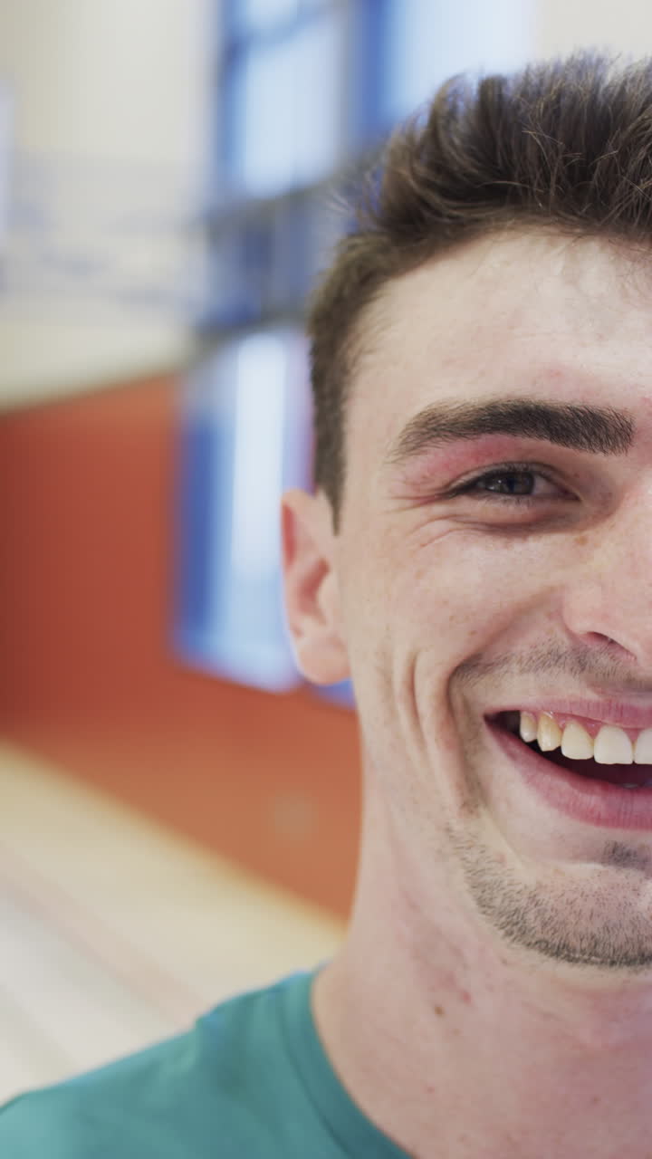 Vertical video half portrait of male caucasian basketball player in indoor court, in slow motion