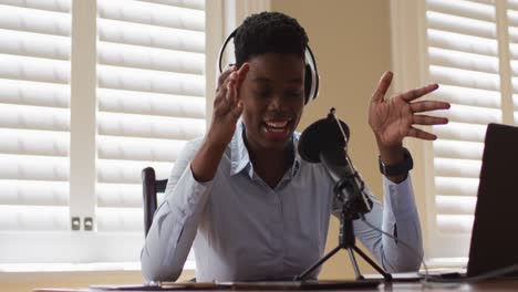 african american woman wearing headphones talking in microphone at home