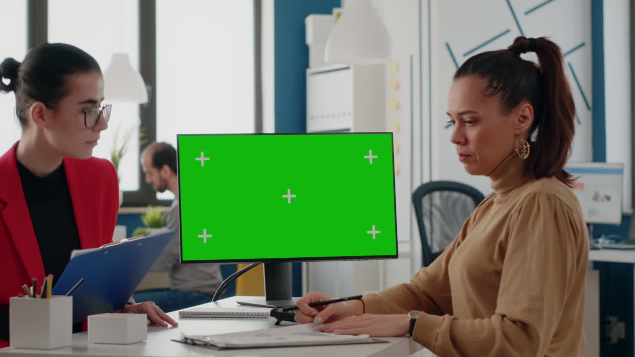 Colleagues working together with green screen on computer display