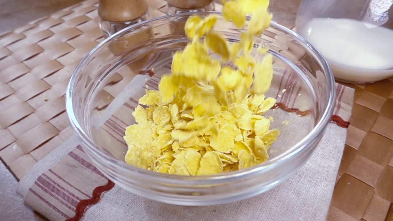 Knusprige gelbe Cornflakes in die Schale für ein köstliches Frühstück mit Milch am Morgen. Zeitlupe mit rotierender Kamerafahrt