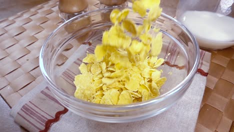 crispy yellow corn flakes into the bowl for the morning a delicious breakfast with milk. slow motion with rotation tracking shot.