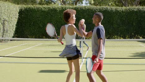 Happy-diverse-group-of-friends-playing-tennis-and-celebrating-at-tennis-court