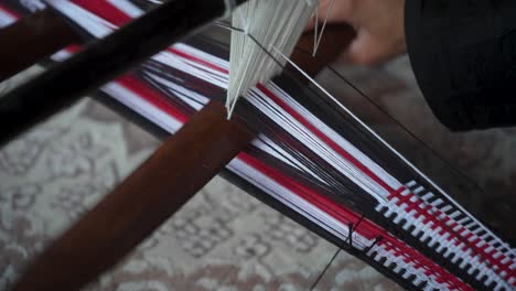 se ven manos tejiendo en un telar tradicional del medio oriente