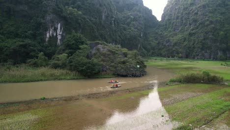 gente navegando en botes sampán ondeando el río ngo dong en la majestuosa campiña de ninh binh, vietnam - tiro en órbita aérea baja
