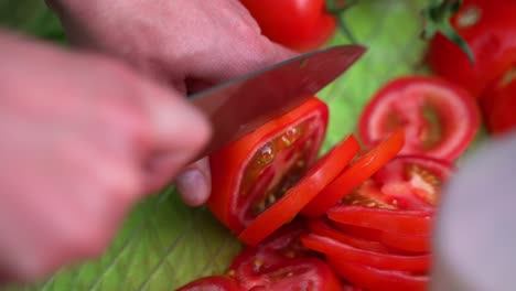 Reife-Frische-Rote-Tomate,-Die-In-Scheiben-Geschnitten-Und-Mit-Einem-Stumpfen-Messer-Geschnitten-Wird,-Nahaufnahme-Der-Kamera,-Die-Während-Des-Hinterhof-Barbecue-Party-Camps-Am-Grünen-Tisch-Aufgenommen-Wurde,-Nahaufnahme,-Die-Auf-Halbem-Weg-Von-60-Fps-Verlangsamt-Wurde