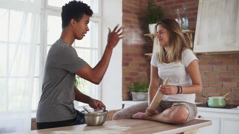 young multi ethnic couple cooking together in the kitchen. attractive african man mixing ingredients in a pot. his girlfriend is