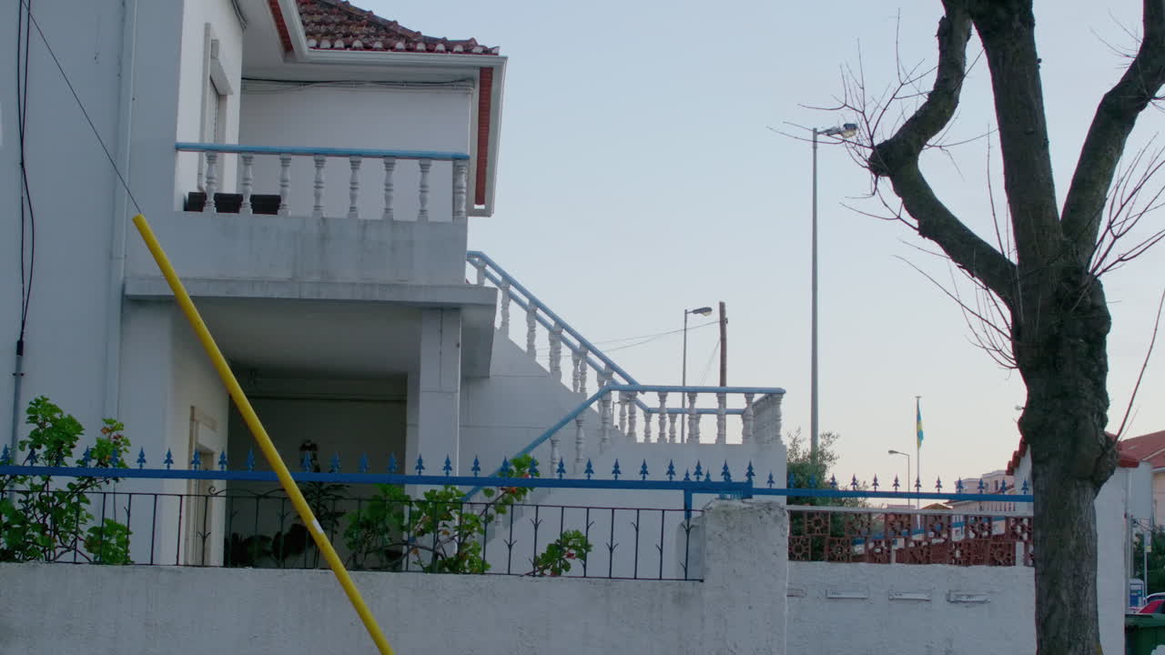 A white house by the street with a small blue railing.