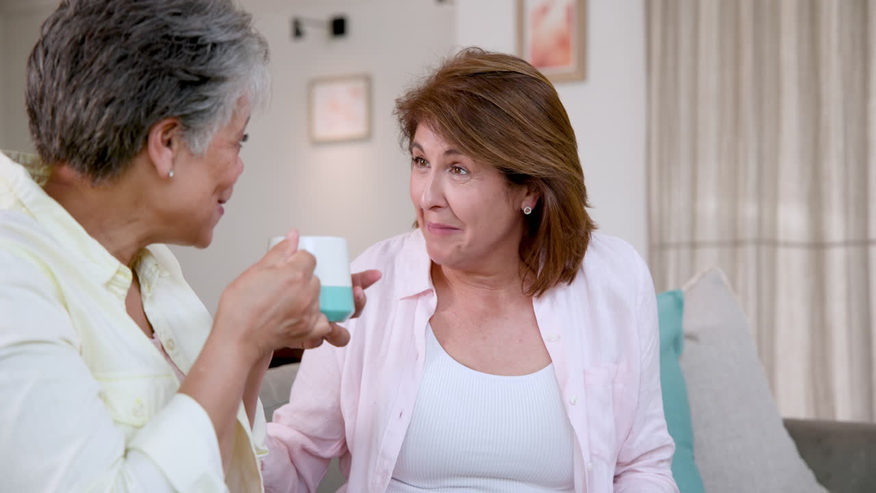Senior women laughing and enjoying coffee together at home, sharing joyful moments