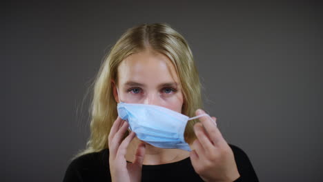 young blonde woman puts on face mask