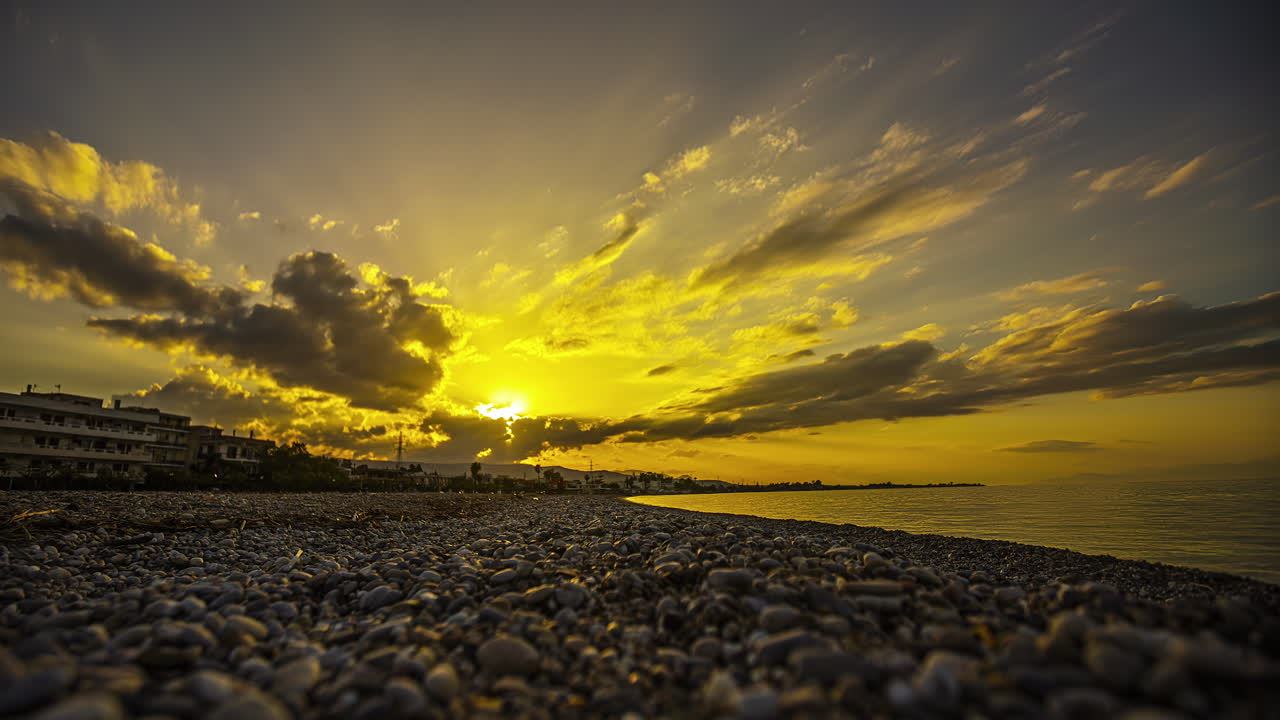 태양은 구름 아래로 가라앉고, 빛의 광선은 비석 해변을 가로질러, 낮은 각도로 아져 나옵니다.