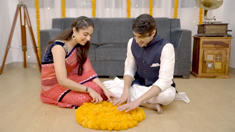 una pareja india haciendo rangoli.