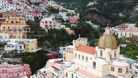 Positano's-colorful-houses-on-a-cliff,-overlooking-the-blue-sea-with-lush-greenery-and-cliffs