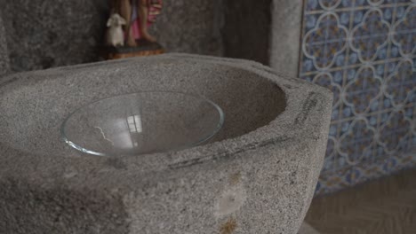 Close-up-of-a-baptismal-font-with-a-glass-bowl-in-a-decorated-chapel