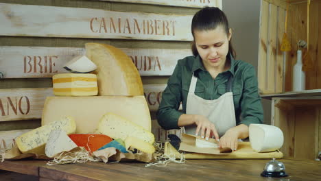 una joven vendedora empaca queso y luego sonríe a la cámara de video hd