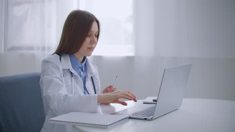 Una-Anciana-Doctora-De-Familia-Está-Consultando-En-Línea-Hablando-Con-Un-Paciente-Por-Video-Chat-En-Una-Computadora-Portátil-Trabajando-Remotamente