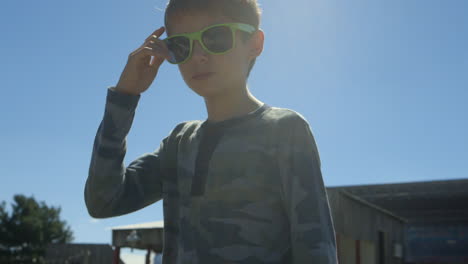 chico genial con gafas de sol verdes mira con confianza a la cámara