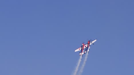 a stunt plane executes precise aerial tricks in clear skies