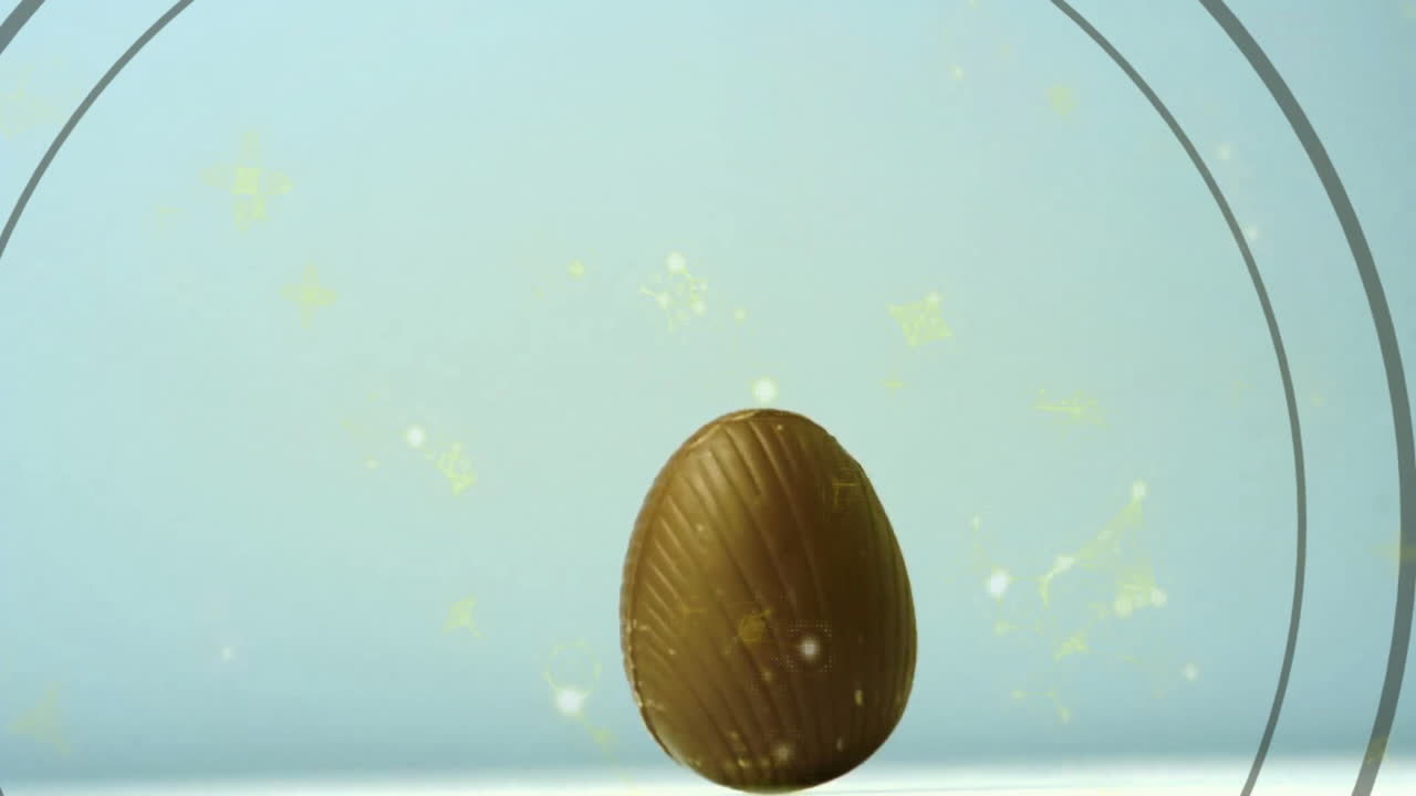 Floating yellow particles around chocolate egg with decorative patterns animation