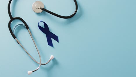 Video-of-stethoscope-and-blue-colon-cancer-awareness-ribbon-on-blue-background-with-copy-space
