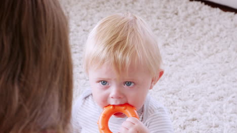 Madre-Joven-Sentada-En-El-Suelo-Con-Un-Niño-Llorando-En-Casa