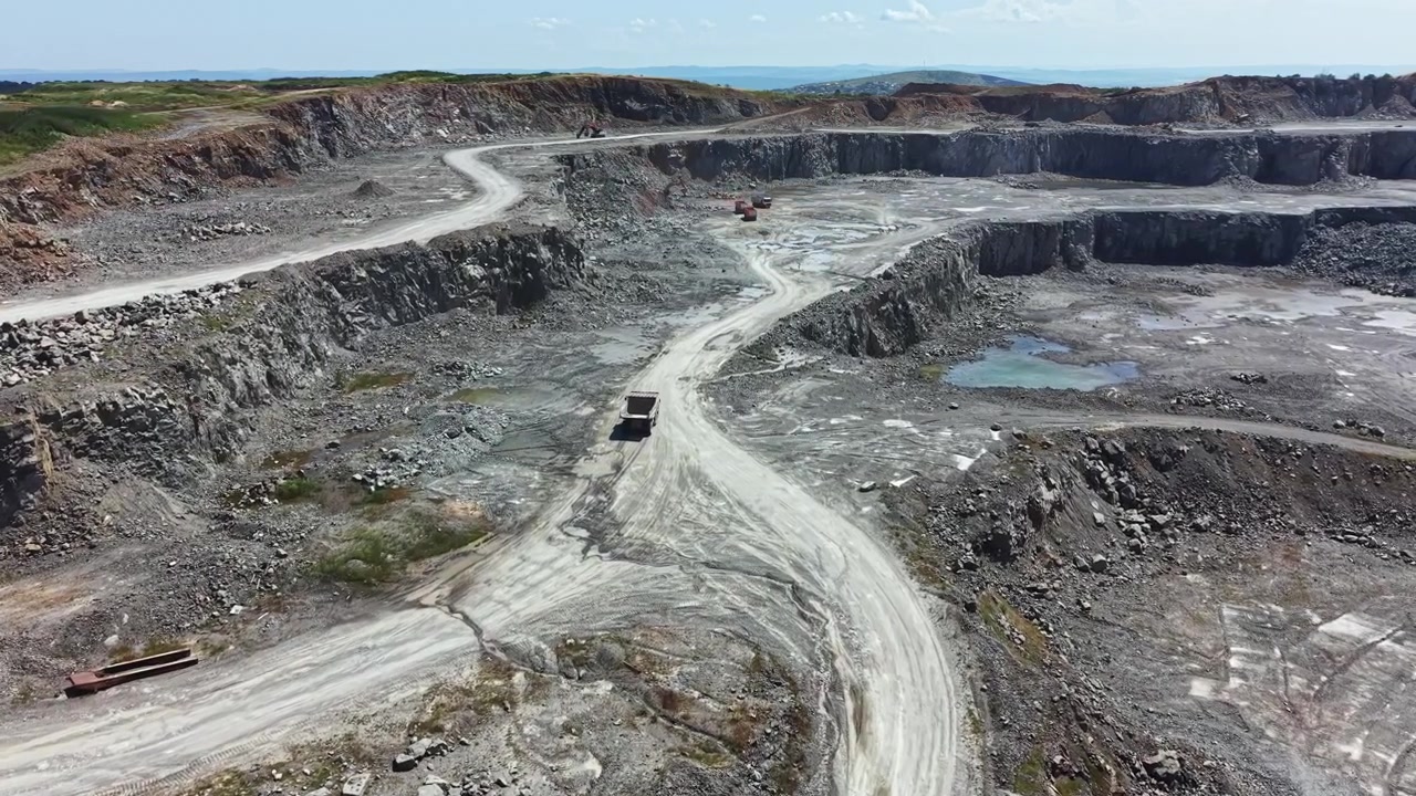 Granite quarry site with heavy machinery and rocky terrain during daytime hours in a remote area with visible work paths