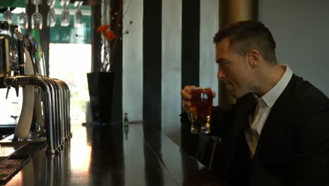 Handsome-businessman-drinking-beer-at-counter-