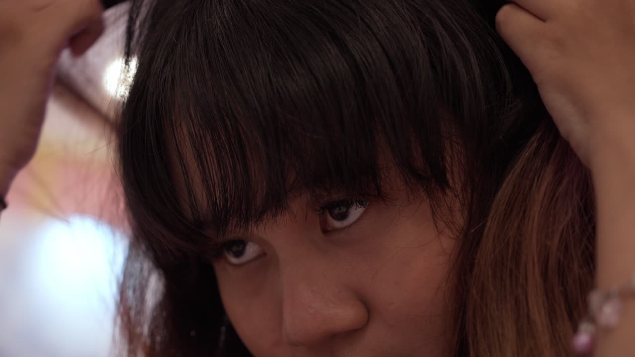 Young Asian Girl Fixing Her Hair Through A Mirror. Close Up Side Profile View Of Her Face.