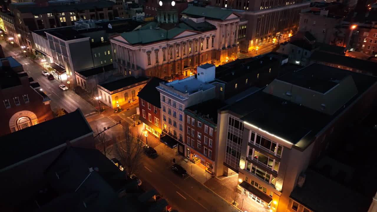 Aerial tilt down at night. Traffic on city street in USA. American buildings in town. Evening establishing shot.