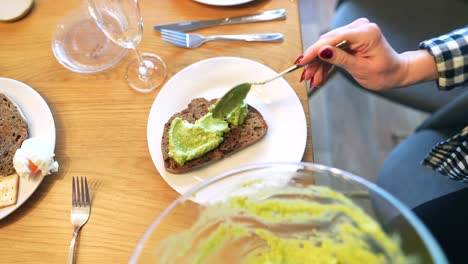 mujer extendiendo aguacate en tostadas