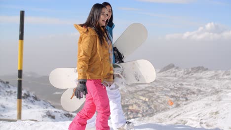 Two-women-carrying-their-snowboards-on-a-mountain