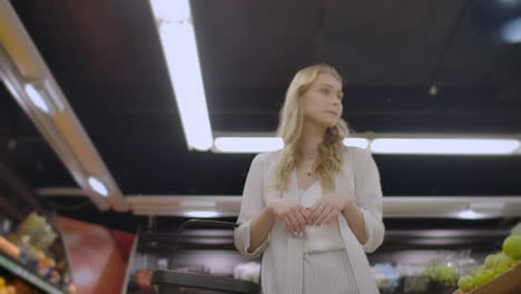 A-woman-buyer-in-a-grocery-store-with-a-basket-walks-between-the-shelves-and-counters-looking-at-the-goods-and-products-a-woman-in-a-supermarket