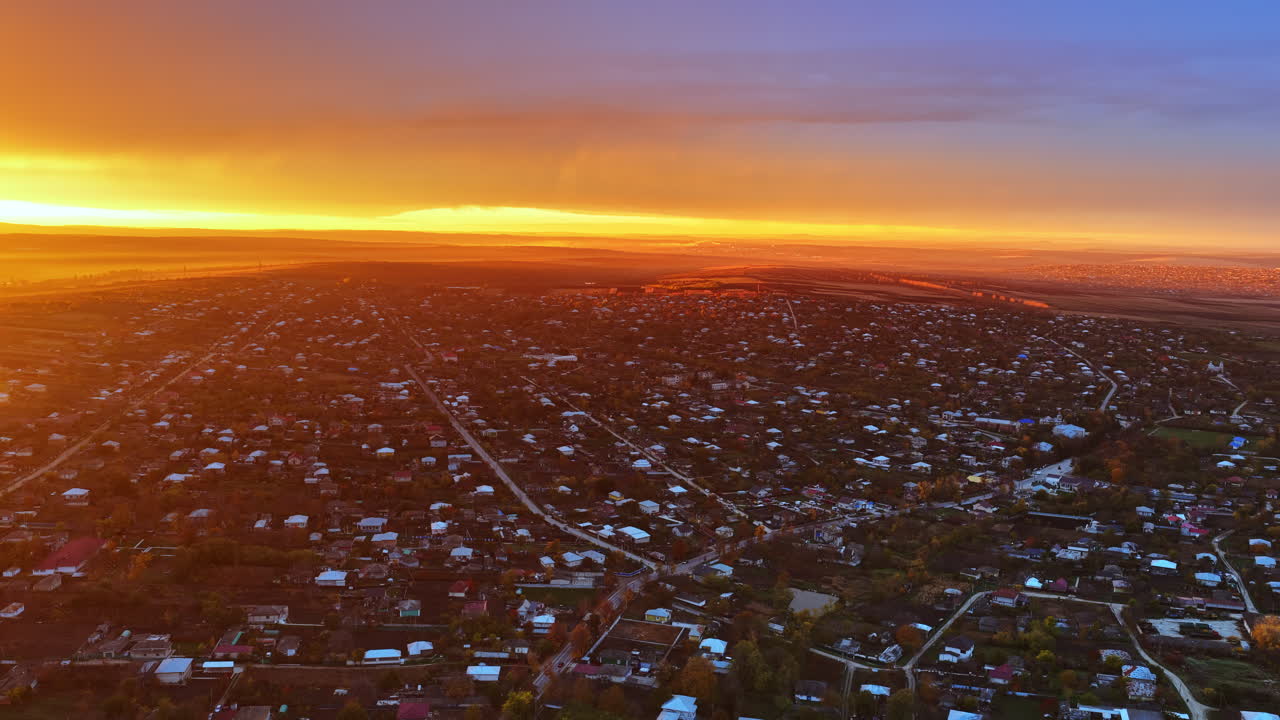 Aerial drone view of a Moldovan town under a glowing orange sunset