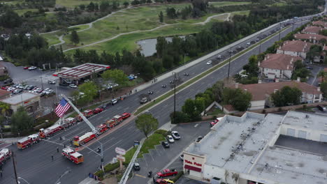 aerial drone of a long funeral procession, fire trucks, police cars, american flags