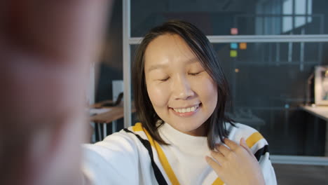 smiling woman taking a selfie in an office