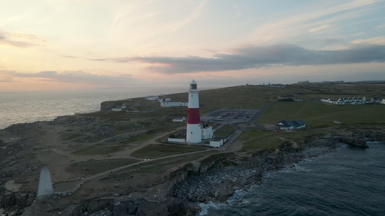 Drone bevæger sig rundt om Portland Bills fyrtårn ved en smuk sommer solnedgang i Dorset, England