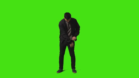 Smiling-Young-Man-Answering-Call-On-Mobile-Phone-Standing-Against-Green-Screen-Studio-Background