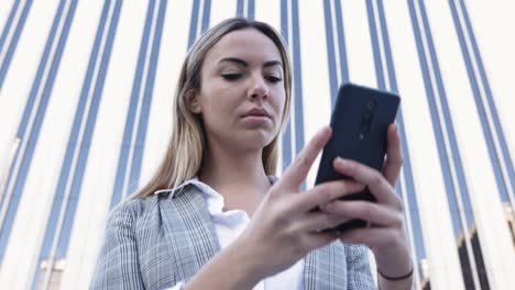 joven mujer de negocios segura usando teléfono móvil en el distrito financiero