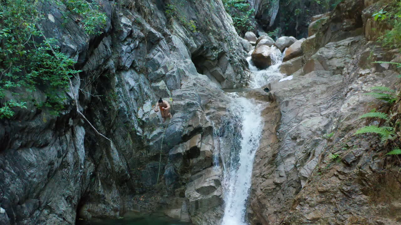 la cabeza del joven salta al agua desde los acantilados rocosos de la cascada, antena