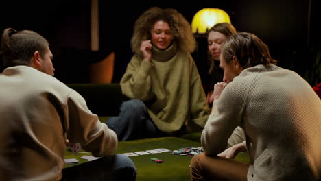 Rear-View-Of-Group-Of-Friends-Playing-Poker-Sitting-On-The-Couch-In-The-Living-Room